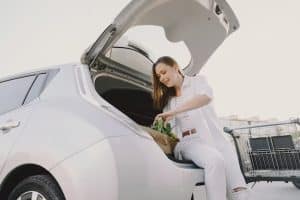 Woman loading groceries into the trunk of a white car in a parking lot, symbolizing the convenience and accessibility offered by Special car financing programs for everyday consumers.