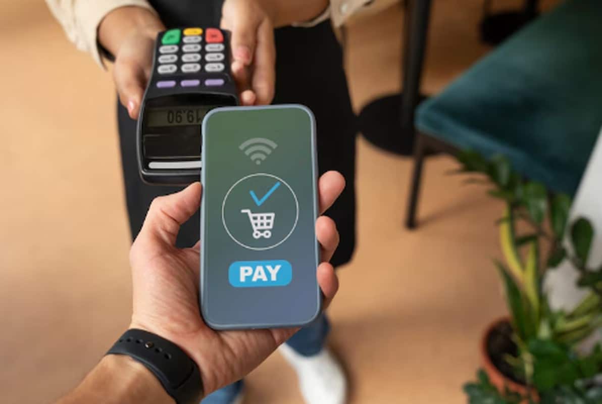 A person holds a smartphone displaying a payment confirmation screen while making a contactless transaction, illustrating the concept of payment automation in a modern retail environment.