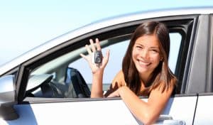 Smiling woman sitting in a car holding the keys, representing the security and confidence of financing with GAP insurance.